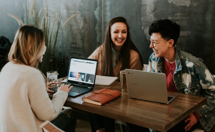 decorative image: a group of three students having fun while working on their laptops